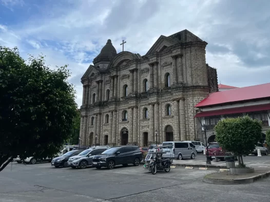 Taal Basilica with cars parked outside.